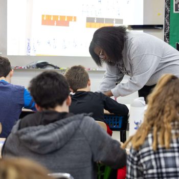 teacher leaning over desk helping a student